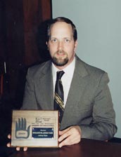 Anthony Wynn holding the Award of Excellence